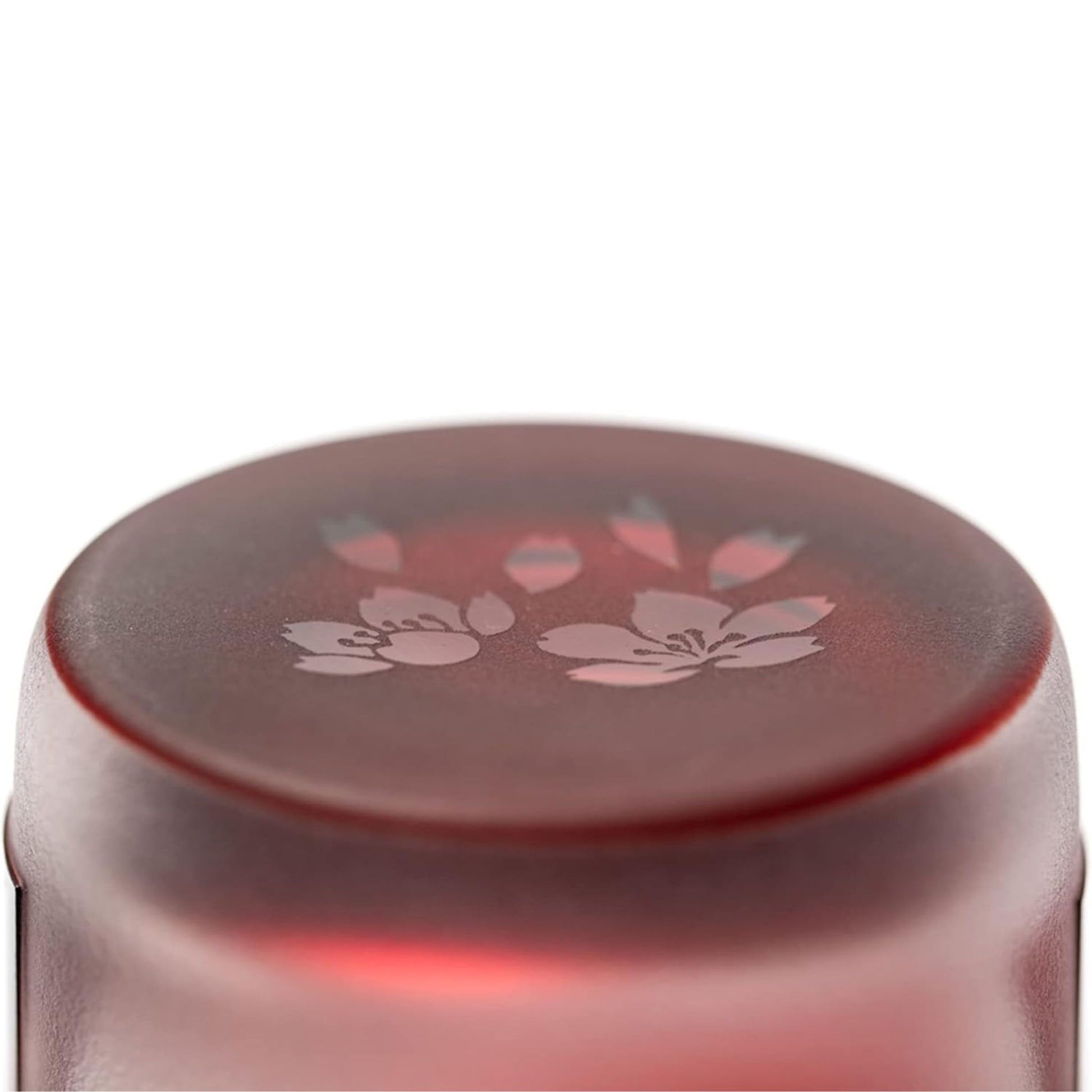 Close-up view of the base of the red whiskey glass, showcasing a delicate sakura flower engraving.