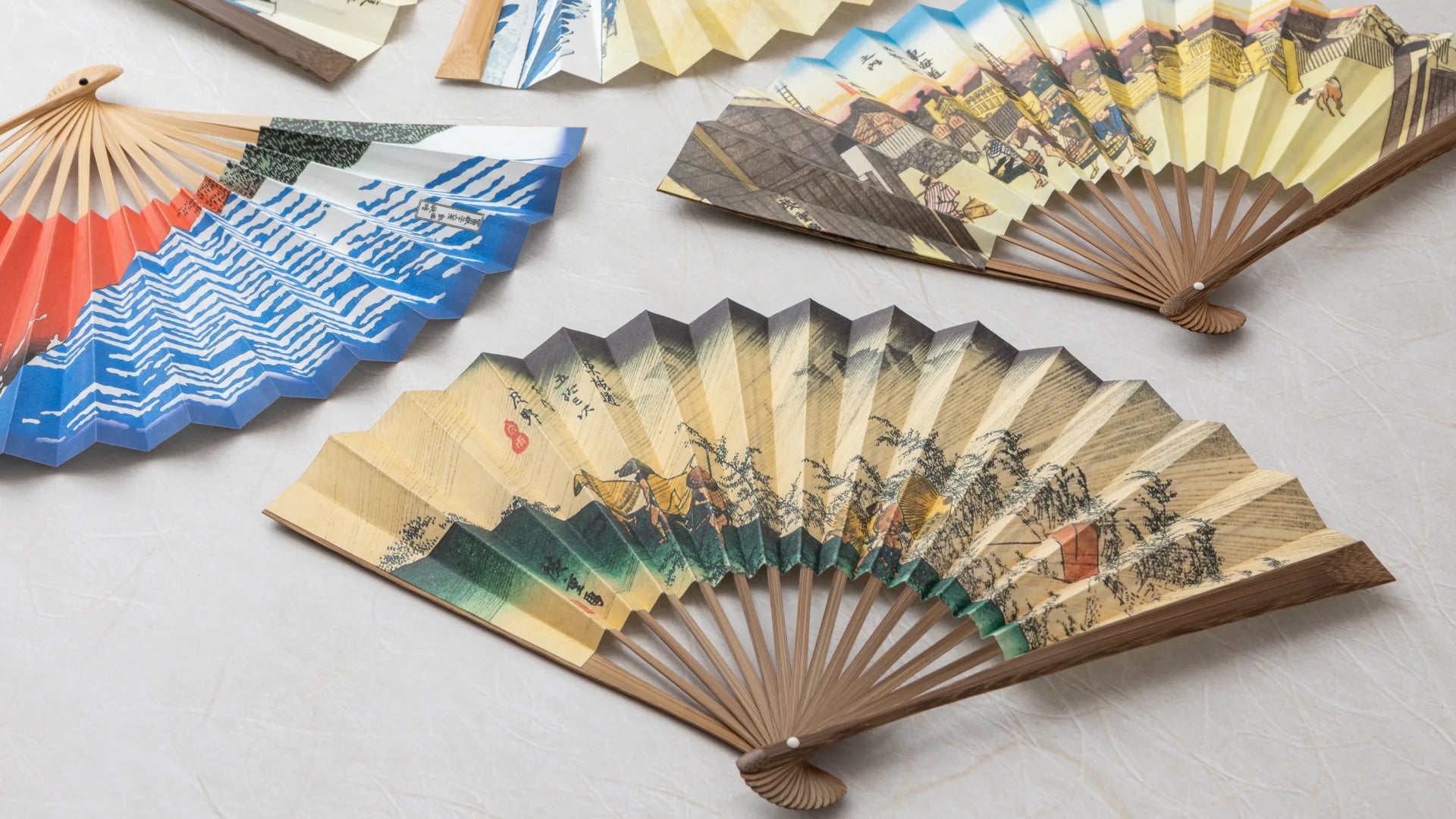 Traditional Japanese fans with artistic designs on a light surface - Omakase