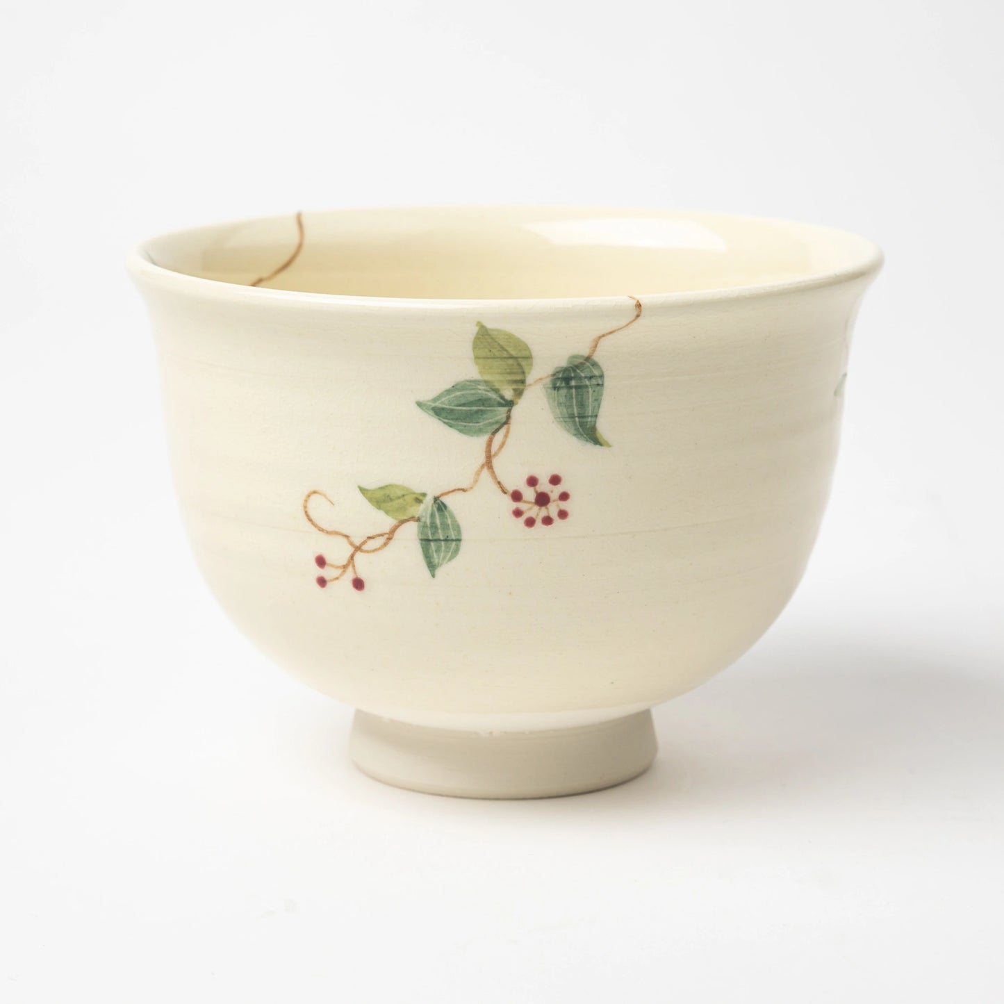 Back view of the matcha bowl, displaying detailed green vines with red berries on a smooth ceramic surface.