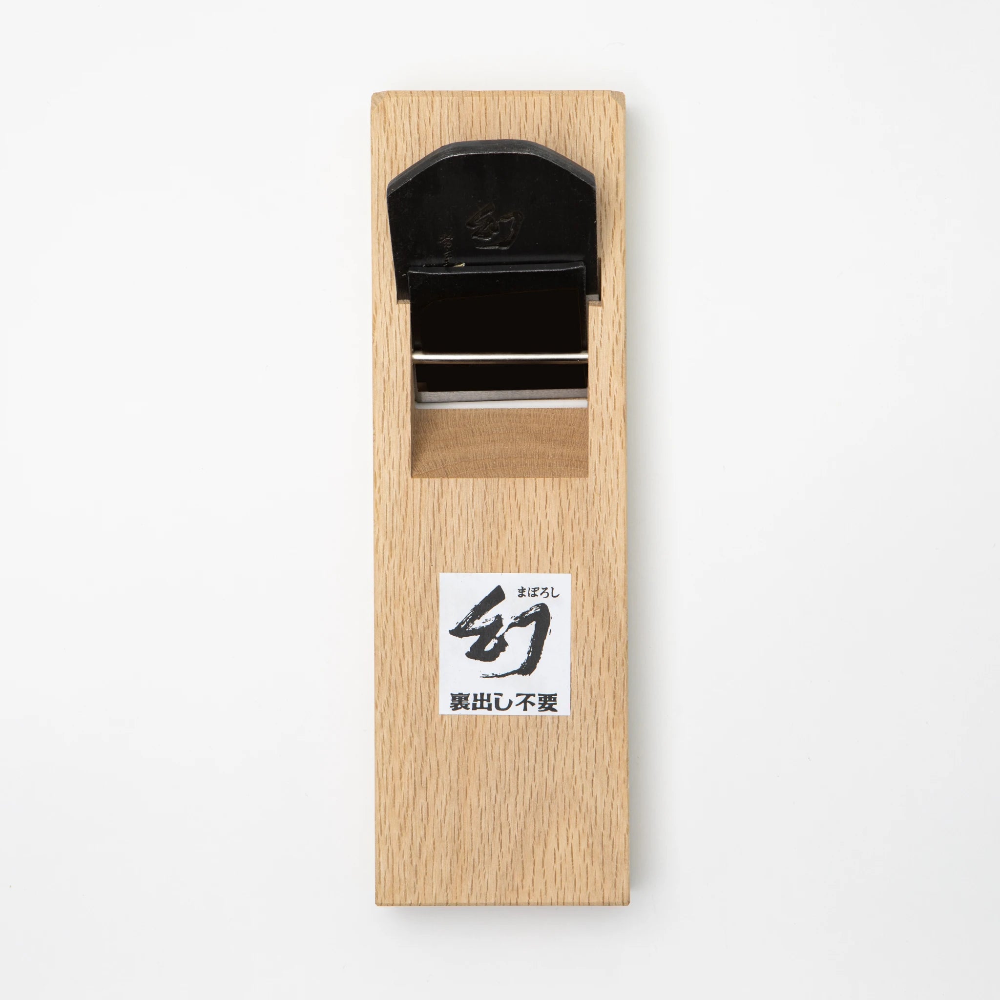 Front view of a Tsunesaburo Maboroshi 70mm smoothing plane showing a white oak dai body with a black-finished blade in the tsutsumi-bori mouth, and a printed Maboroshi label with uradashi-free notation affixed to the lower body.