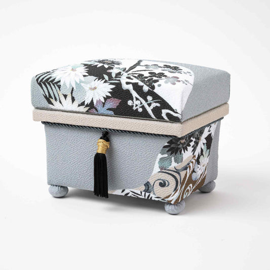 ngled view of the Kaga Yuzen Michinaga Accessory Box, showcasing intricate floral motifs in black, white, and gray tones on a textured light gray background. The box features a black tassel with gold accents, adding an elegant touch to the design.