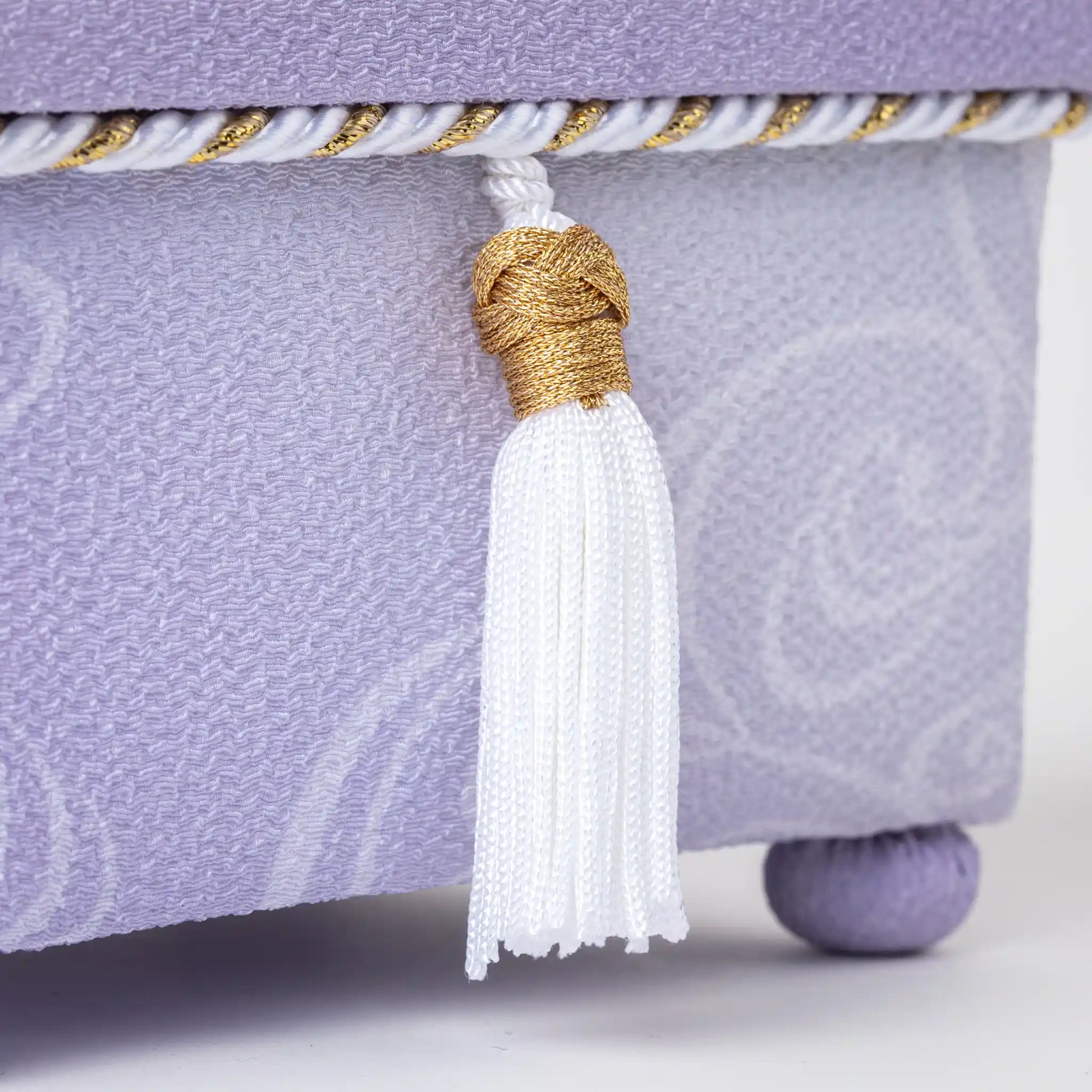 Detailed close-up of the white tassel with gold accents on the Kaga Yuzen Wisteria Accessory Box, showcasing intricate floral motifs on the lavender fabric.